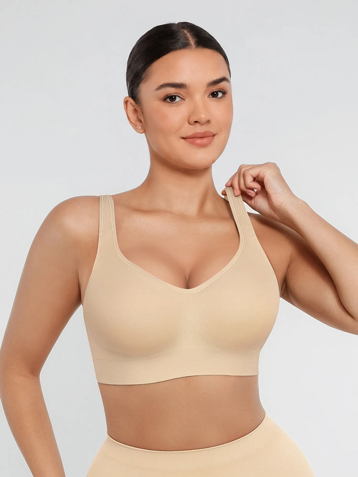 Woman wearing a beige sports bra on a plain background