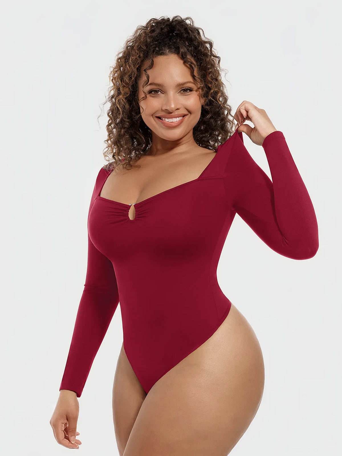 Front view of a model in a burgundy long-sleeve slimming bodysuit featuring a U-neckline with metallic ring detail and tummy control