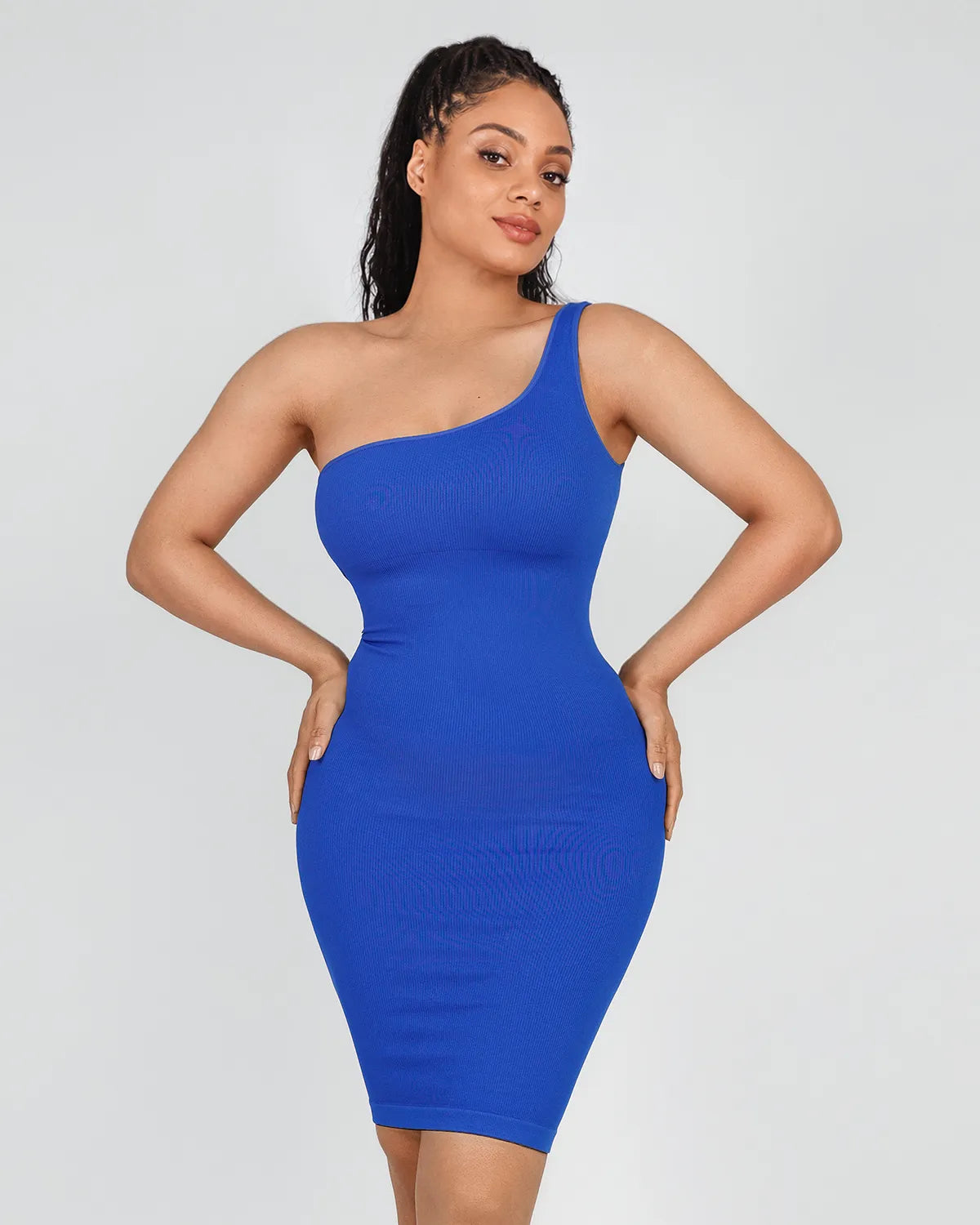 A woman modeling a bright royal blue one-shoulder bodycon dress against a light gray studio background.
