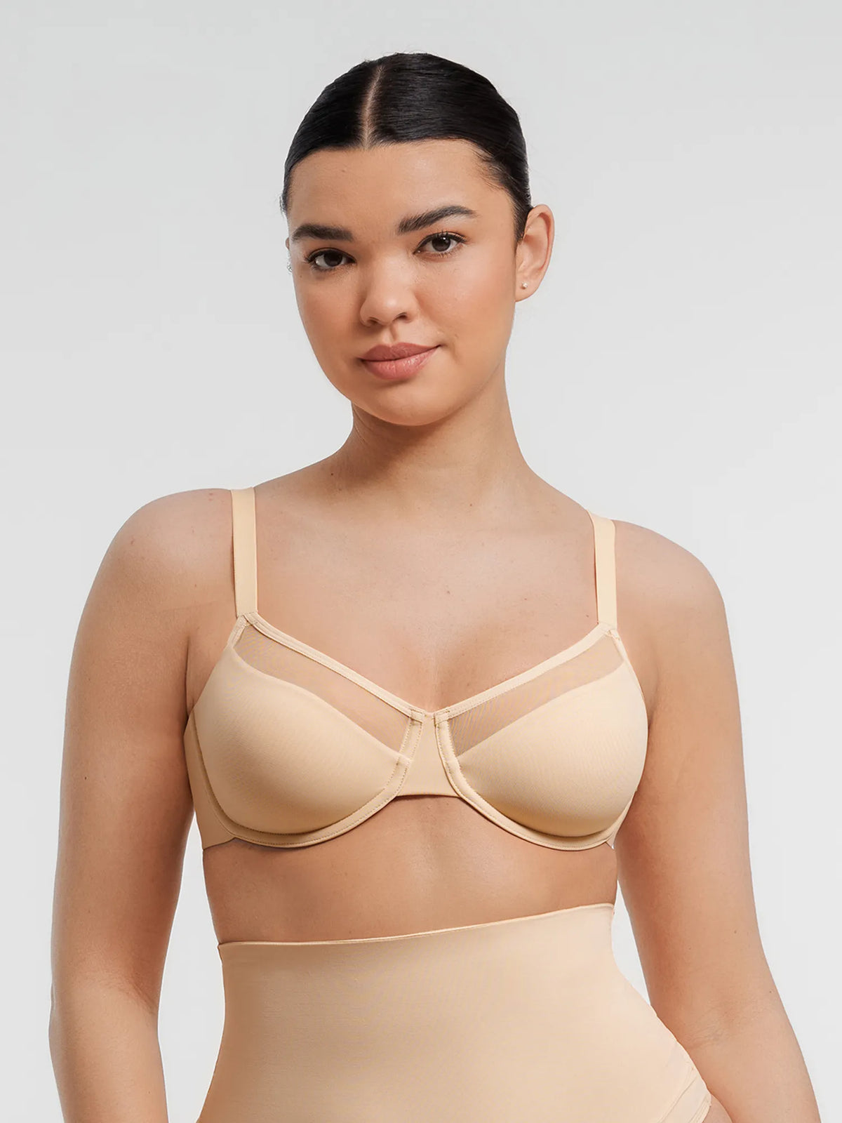 ront view of a model in a light beige unpadded underwire bra with full-cup coverage and sheer mesh upper trim